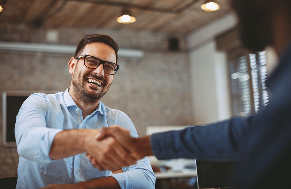 man smiling whilst shaking hands